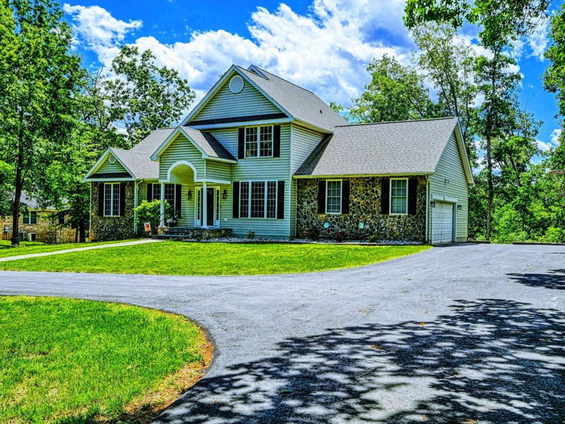 Exterior Front - Circular driveway approach with the home, detached shed, and mature shade trees.