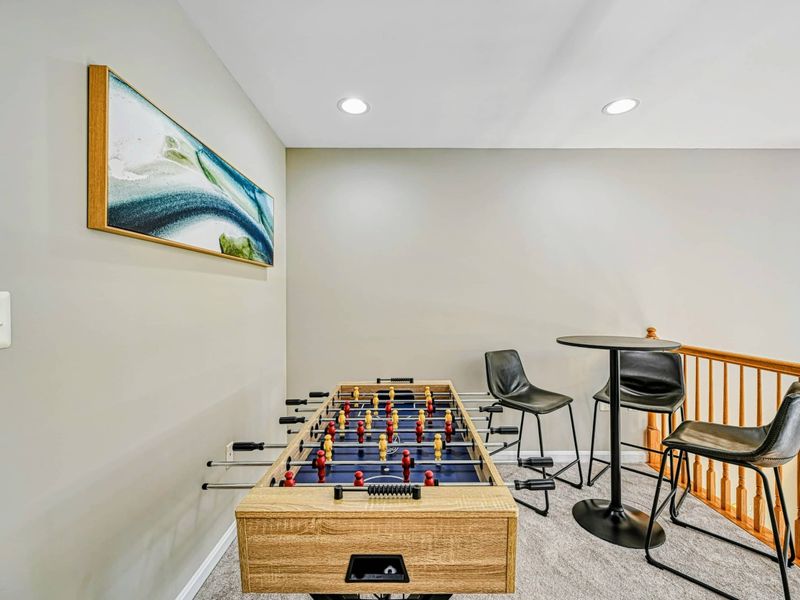 Loft Game Area - Foosball table with ocean-inspired wall art, bistro table, and entry to the upper bedrooms.