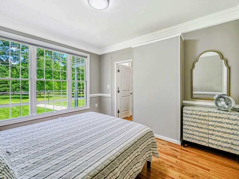 Bedroom 2 - Alternate showing the large bay window with garden views, gold-frame mirror, and chevron-pattern dresser.