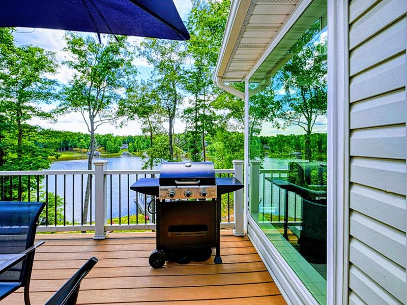 Deck - Gas grill on the side deck with lake views through the trees and railing.