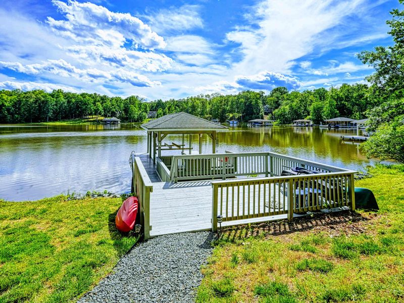 Waterfront - Sundeck with white railings and covered gazebo extending into the lake from the green lawn.