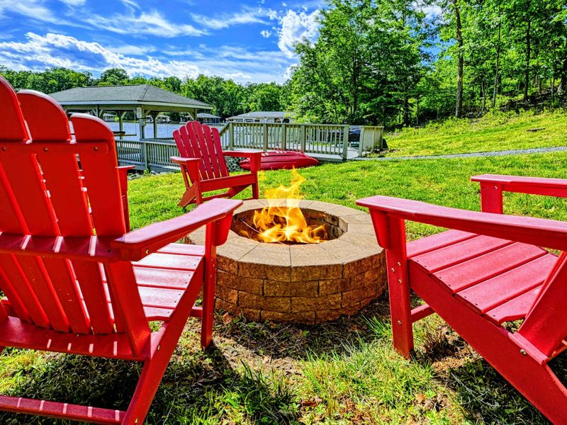 Fire Pit - Alternate angle of the stone fire pit with red Adirondack chairs, dock, and lake views.
