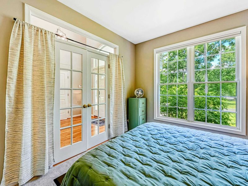 Bedroom 3 - Alternate showing the French doors to the en suite, garden-view window, and green accent chest.