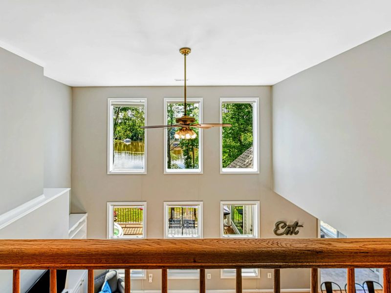 Loft Overlook - View from the loft railing through the ceiling fan and six tall windows with lake views below.