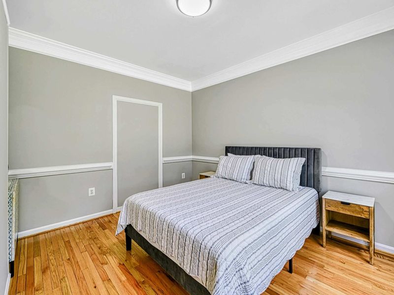 Bedroom 2 - Queen bed with charcoal channel headboard, striped bedding, crown molding, and chair rail on the main level.
