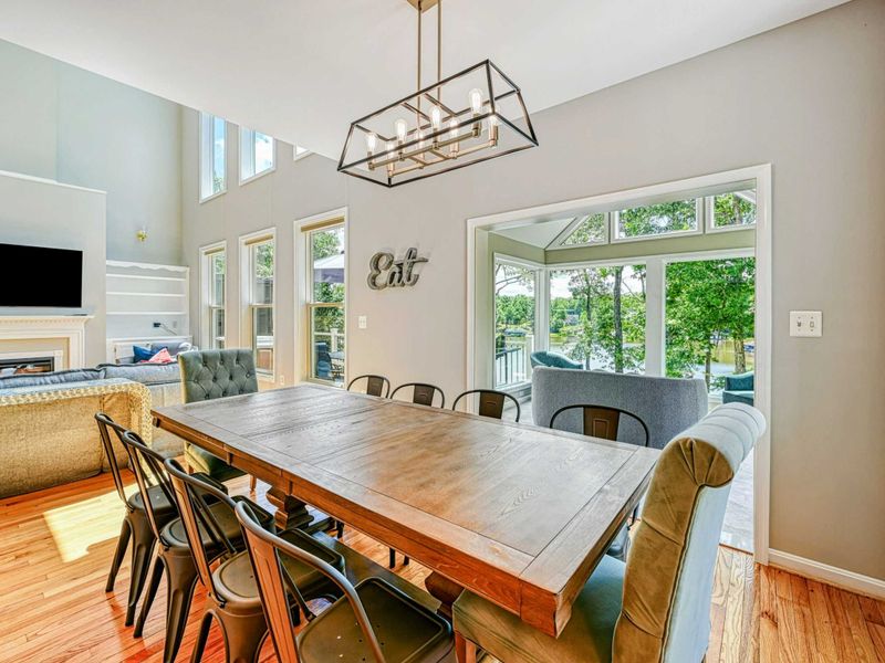 Dining Room - Farmhouse table for ten with industrial metal chairs, cage chandelier, and sightlines to the sunroom and lake.