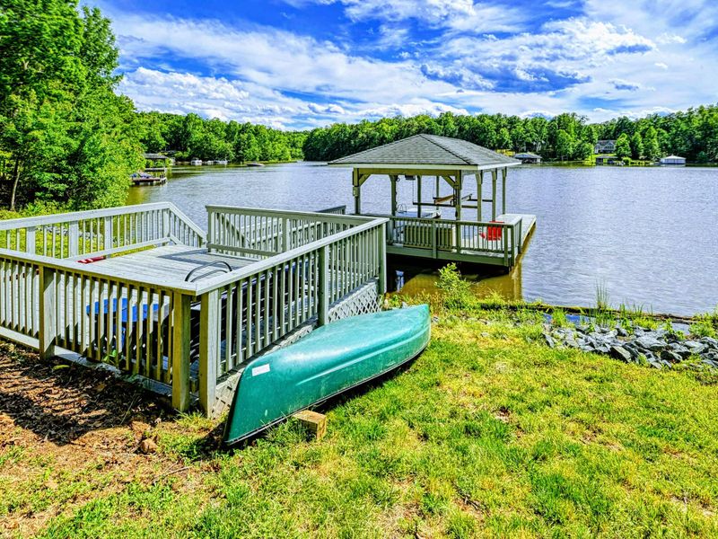 Dock - Alternate view of the dock, sundeck, and green canoe stored at the shoreline with the cove beyond.