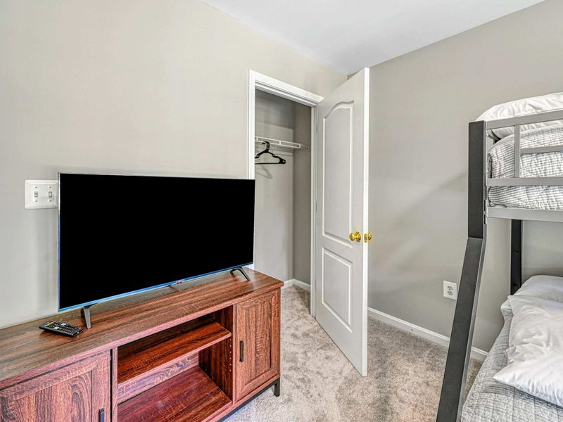 Bedroom 4 - TV on a wood stand with closet and bunk bed for entertainment on the upper level.