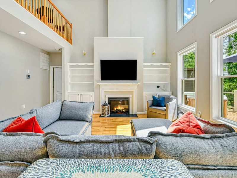 Living Room - Sectional facing the fireplace and TV with built-in bookshelves, loft railing above, and colorful throw pillows.