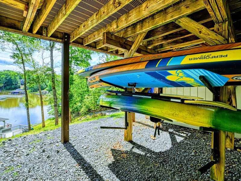 Kayak Storage - Colorful kayaks and paddleboards stored on racks under the deck for guest use.