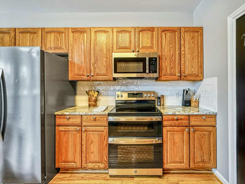 Kitchen - Oak cabinets with granite counters, stainless steel range, microwave, and subway tile backsplash.