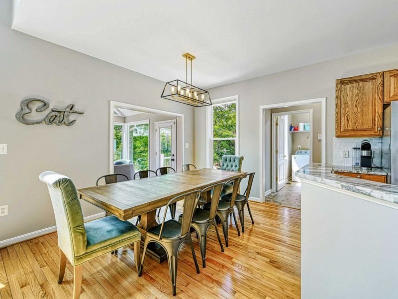 Dining Room - Alternate view of the farmhouse table with kitchen pass-through and sunroom entry visible.