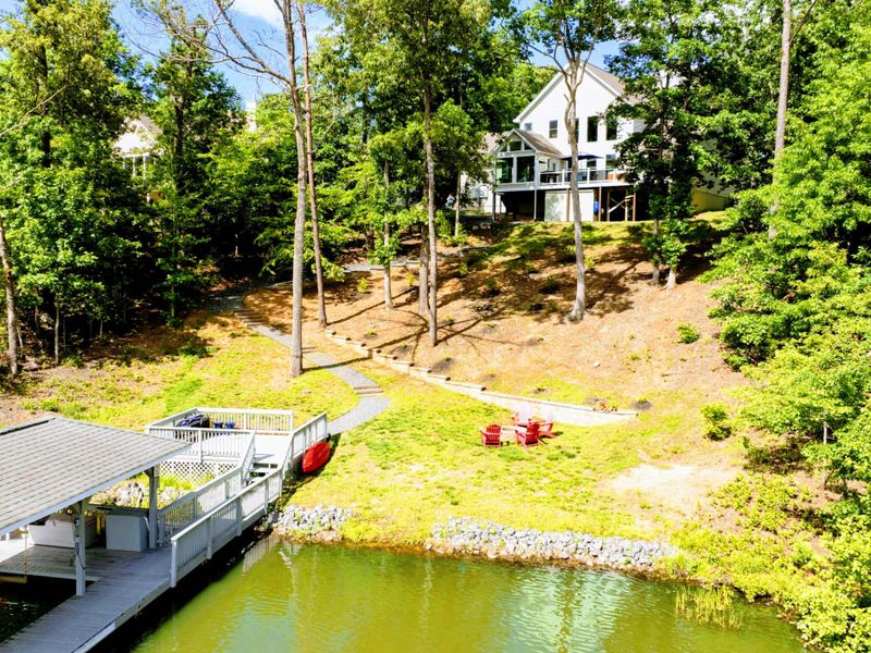 Aerial - Wider view of the property from the lake, showing the home among the trees with the dock and cove.