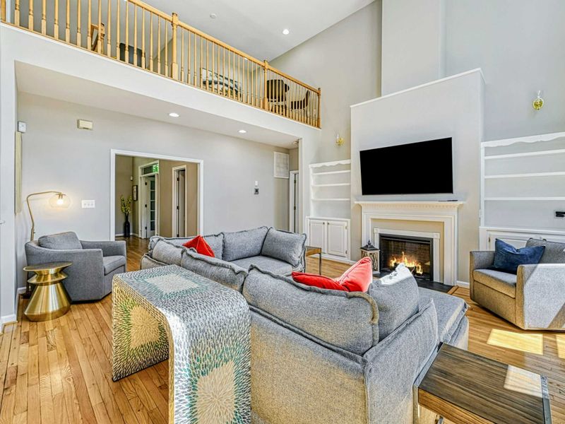 Living Room - Alternate showing the fireplace wall, accent chair, loft railing, and hallway to the bedrooms.
