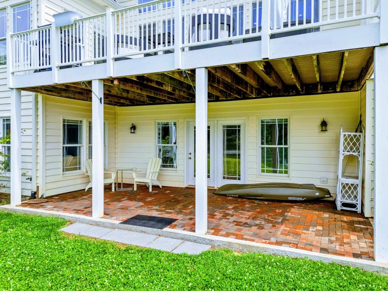 Lower Patio - A covered lower-level patio with French doors opening directly to the backyard and lake beyond.