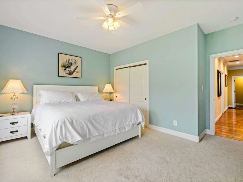 King Bedroom - The king bed with closet access and a view down the hallway, plus a heron print above the headboard.