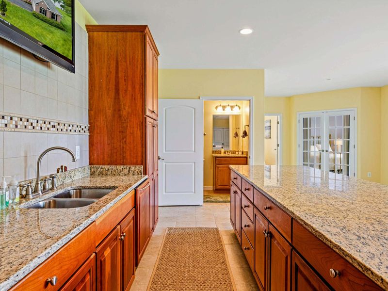 Wet Bar and Bath - The bar from behind, looking toward the lower-level full bath and the open entertaining space.