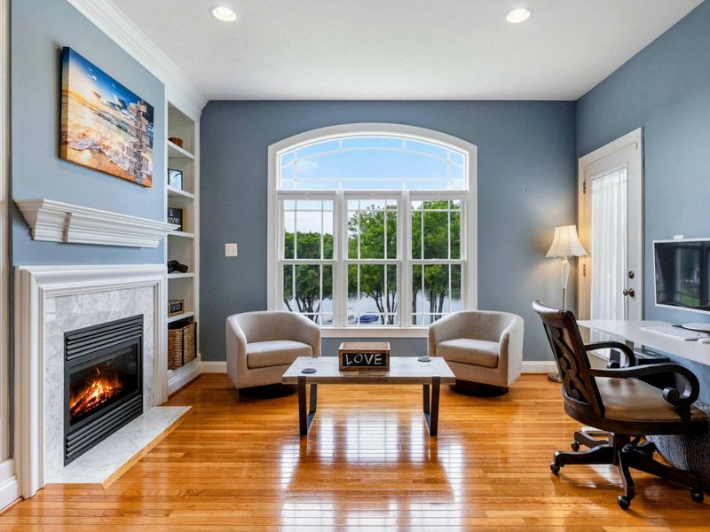 Primary Sitting Area - The fireplace with marble surround, built-in bookshelves, and a large arched window framing the lake.