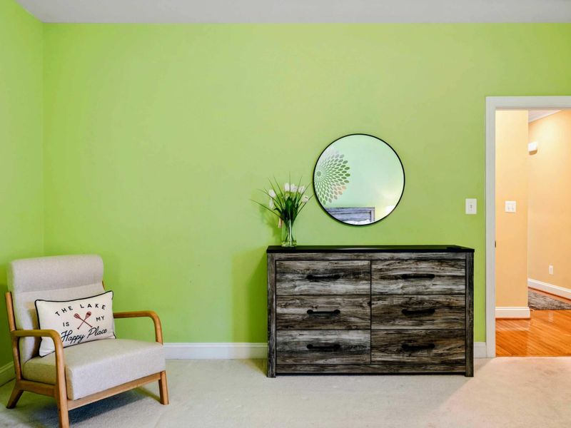 Bedroom Detail - A reading chair and weathered-wood dresser with a round mirror add character to the green guest room.