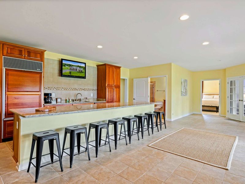 Wet Bar Detail - The full bar with eight stools, a mounted TV, and bedroom access on either side for the lower level guests.