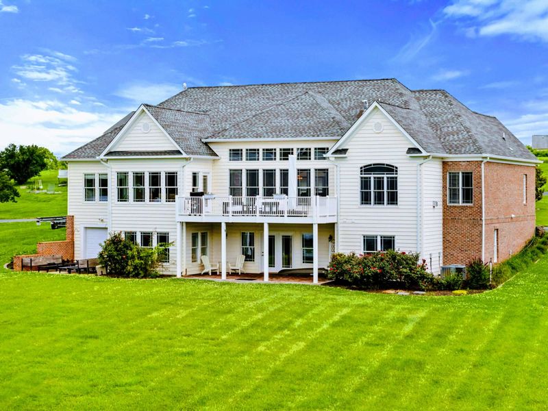 Rear Exterior - The full rear facade with brick details, a covered lower patio, and a wraparound upper deck.