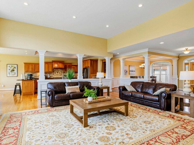 Great Room - From the entry, the open layout draws you in with hardwood floors, warm tones, and the kitchen columns framing the space.