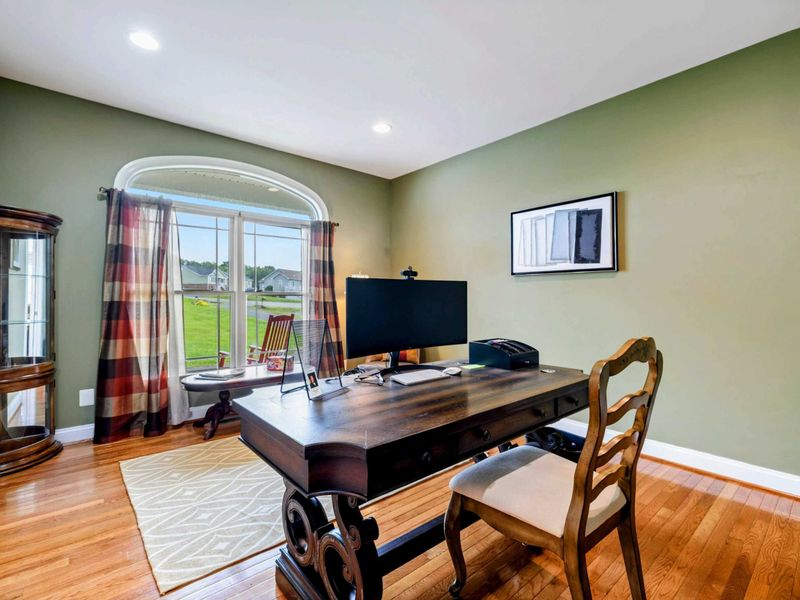 Home Office - A second view showing the desk, reading chair, and natural light filling the room through plaid curtains.