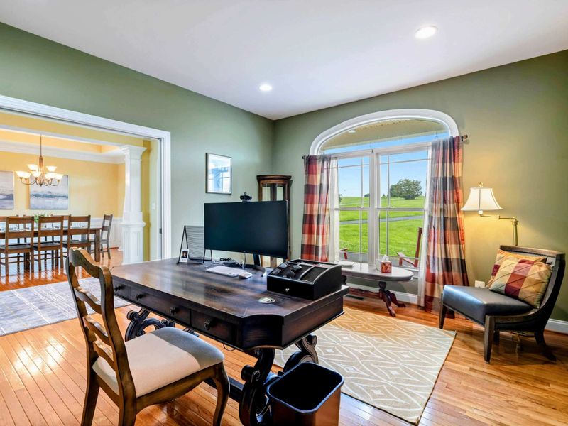 Home Office - A dedicated workspace with a large desk, monitor, and an arched window overlooking the front lawn.