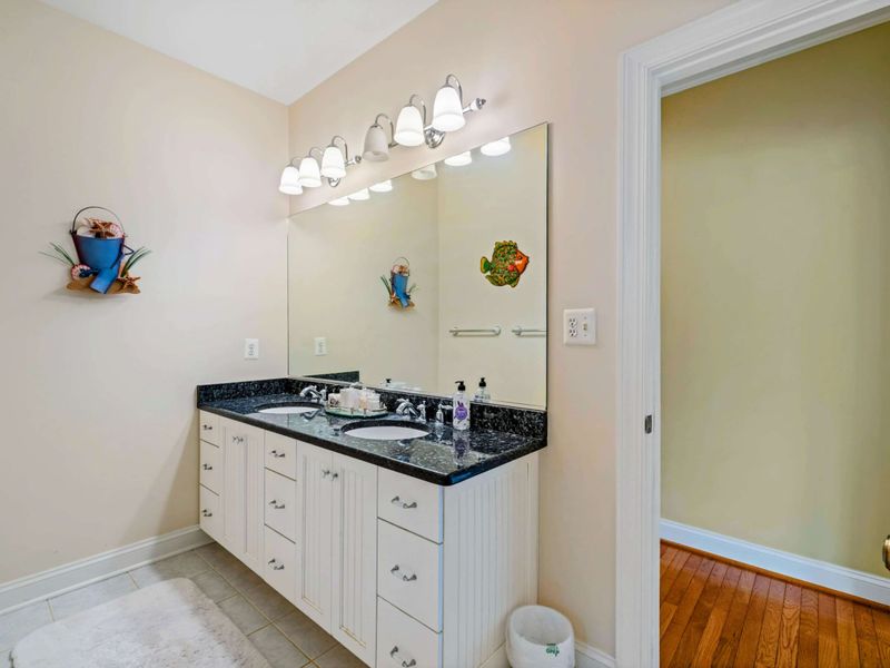 Shared Bath Vanity - A double vanity with black granite, white beadboard cabinetry, and playful fish and beach decor.