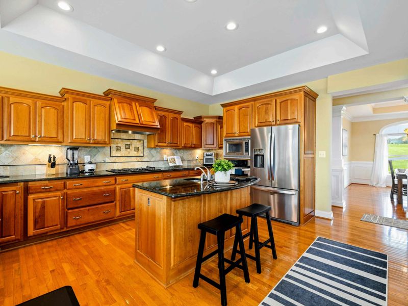 Gourmet Kitchen - Rich wood cabinetry, granite countertops, a center island with bar seating, and stainless steel appliances make this kitchen ready for any meal.