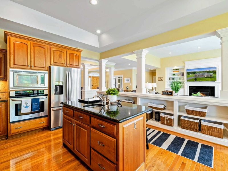Kitchen Appliances - Double wall ovens, a built-in microwave, and stainless steel refrigerator with the great room fireplace in view.