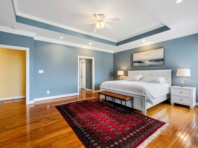 Primary Suite - A wider view showing the spacious layout, walk-in closet access, and the hallway to the ensuite bath.