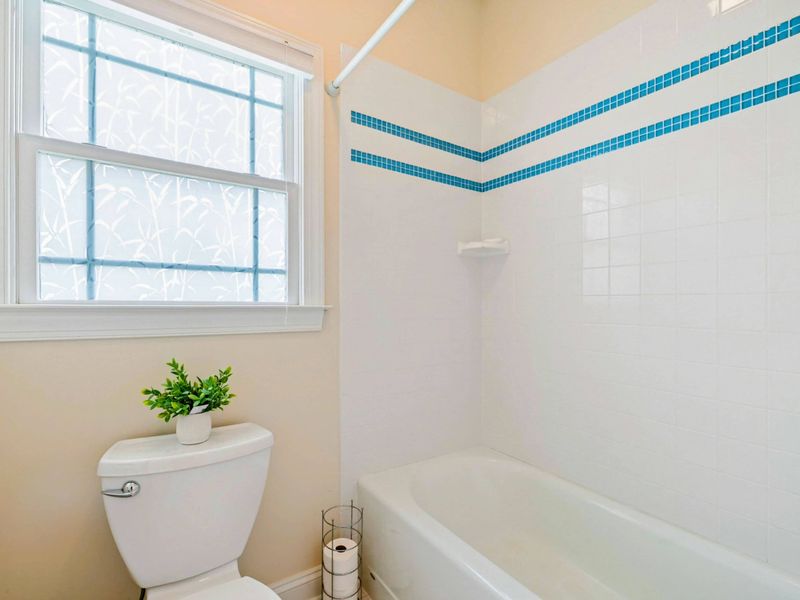 Tub and Shower - White tile with a turquoise accent stripe brings a clean, beachy feel to the shared bath.