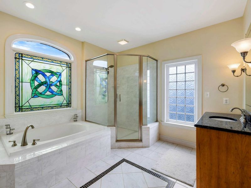 Primary Ensuite - The full bath with soaking tub, stained glass, corner shower, and a granite-topped vanity.