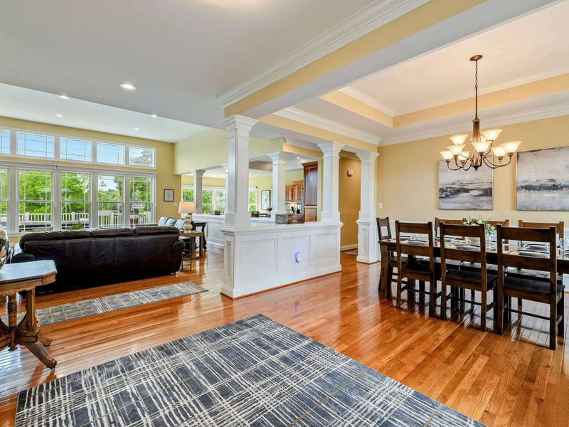 Formal Dining - A large farmhouse table beneath a chandelier seats eight comfortably, with the open living and kitchen areas just beyond.