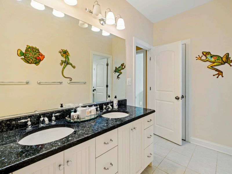 Shared Bath - A double vanity with black granite countertops and playful coastal wall art adds personality to the lower-level bath.