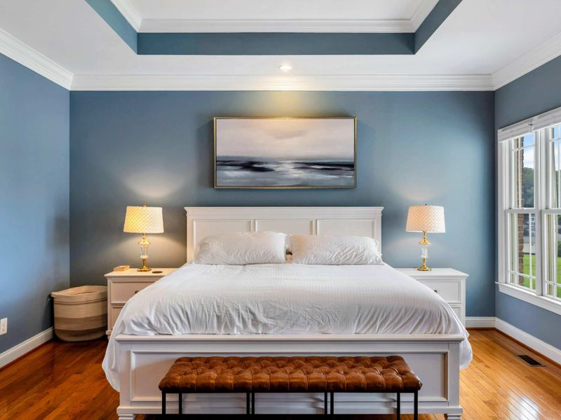 Primary Suite - White bedding, ocean-inspired art, and matching nightstands create a calm, restful setting.