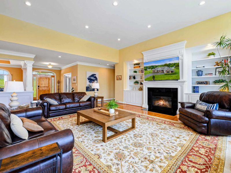 Great Room - Plush leather seating and a large coffee table sit beneath soaring ceilings, with the open kitchen just beyond.