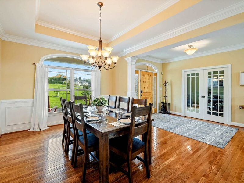 Dining and Entry - The formal dining room near the front entry, with an arched window, French doors, and views of the green lawn.
