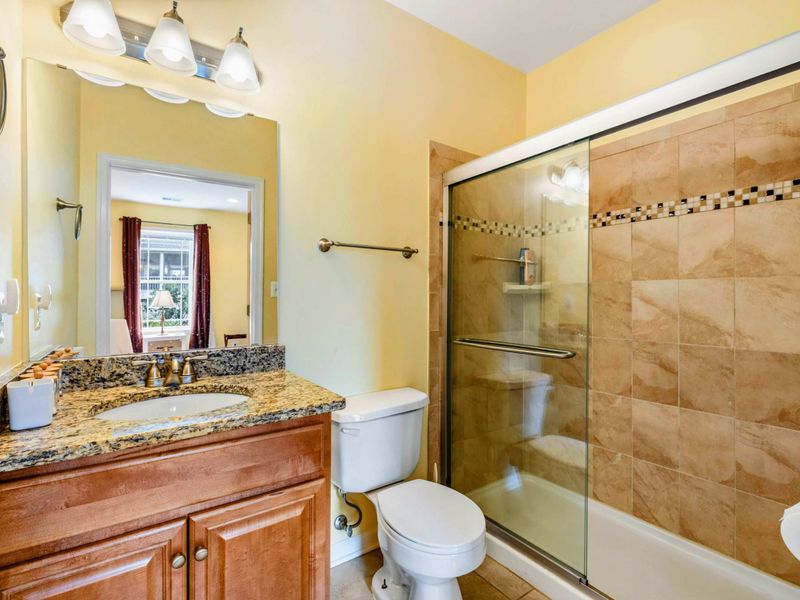 Lower Ensuite Bath - A granite vanity and glass-enclosed tub with mosaic tile accents give this bath a polished, spa-inspired feel.