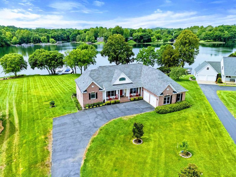 From Above - The full property comes into view with its waterfront position, manicured yard, and easy access to the dock and lake.
