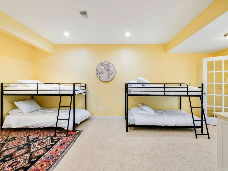 Bunk Room - A wider view shows the full layout with globe art, a dresser, and French doors connecting to the queen bedroom next door.