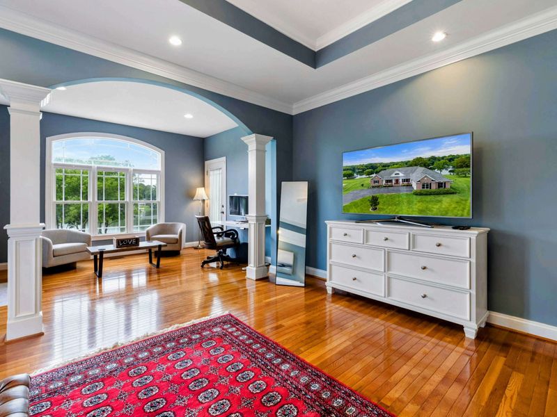 Primary Sitting Area - The TV and dresser near the arched opening, with the fireplace and built-in shelves framing the lake-view window.