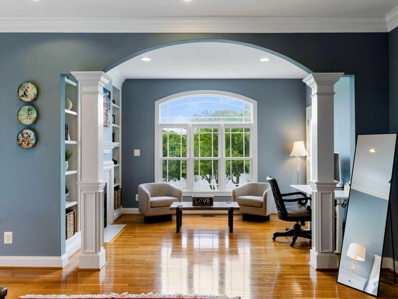 Primary Sitting Area - An arched alcove with built-in shelves, accent chairs, a desk, and a large window overlooking the lake.