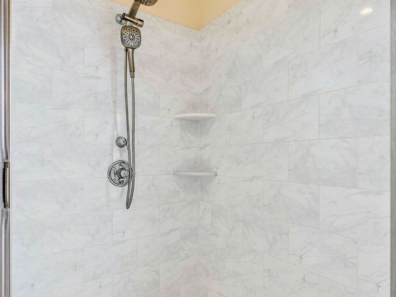 Shower Detail - Marble tile walls and a handheld showerhead inside the spacious walk-in shower.
