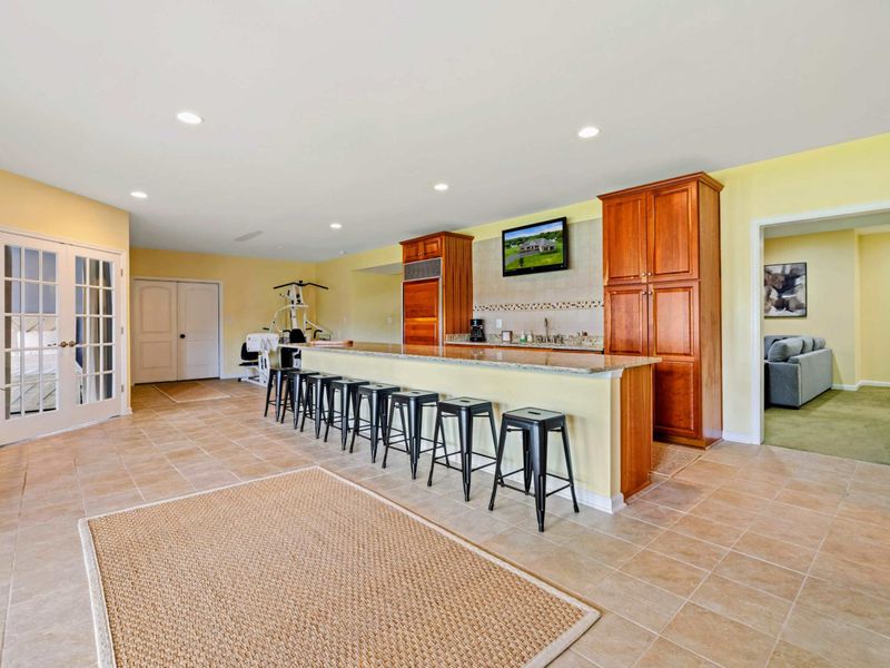 Lower Level Overview - The open layout from another angle, showing French doors to the patio and doorways to bedrooms and bath.