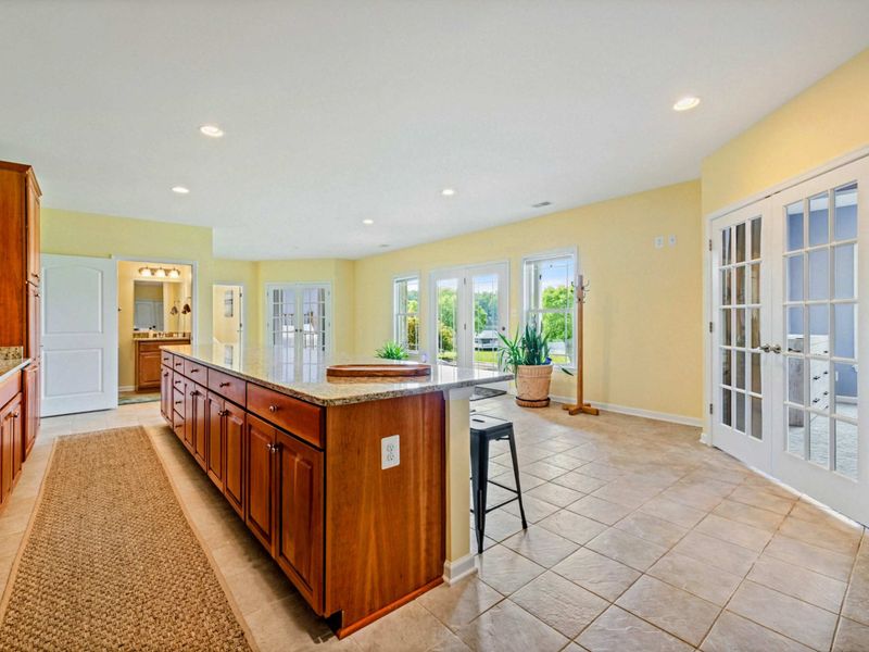Lower Level - A spacious open area with a wet bar island, tile floors, French doors to the backyard, and access to lake-level bedrooms.