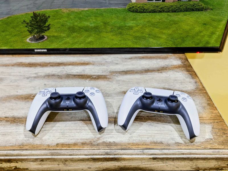 Gaming Detail - Two PlayStation controllers sit ready on the console, waiting for the next round of friendly competition.
