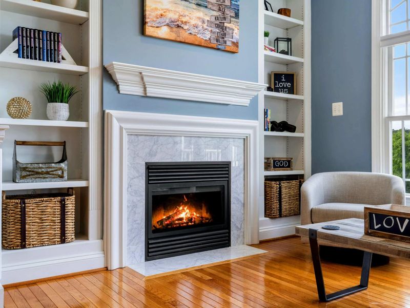Primary Fireplace - A closer view of the marble fireplace, curated bookshelves, and the arched lake-view window.
