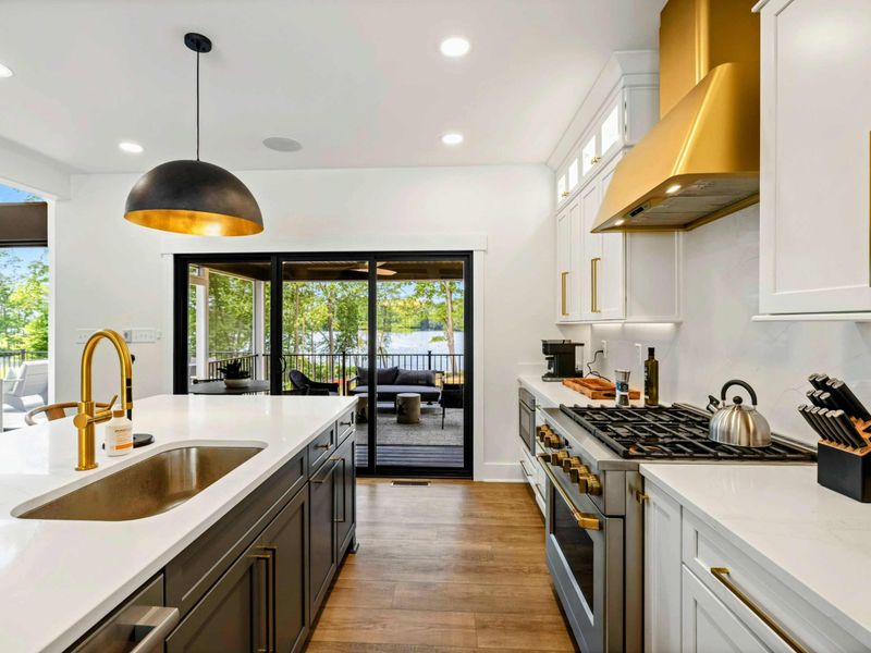 Kitchen - A gold faucet and professional range sit alongside sliding doors that open to the screened porch and lake beyond.